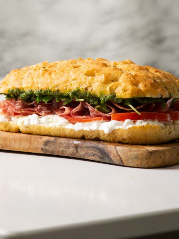 large focaccia sandwich on wooden chopping board on marble island
