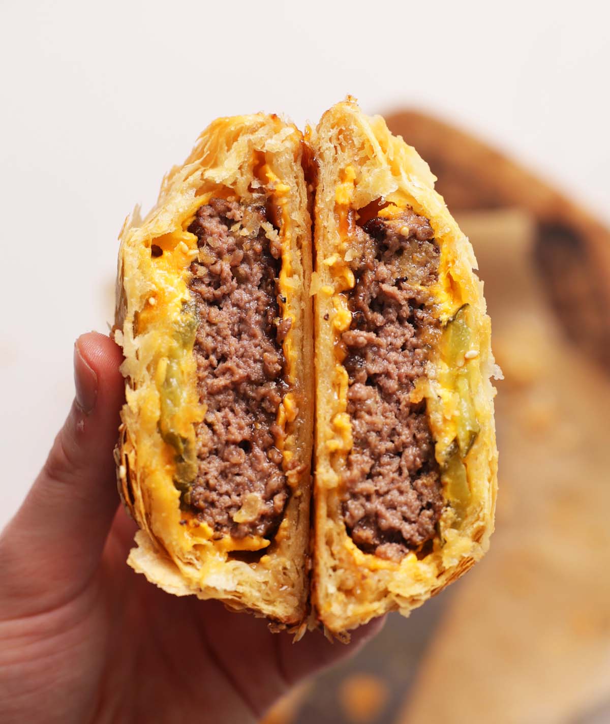 close up overhead shot of hand holding ground beef wellington sliced open