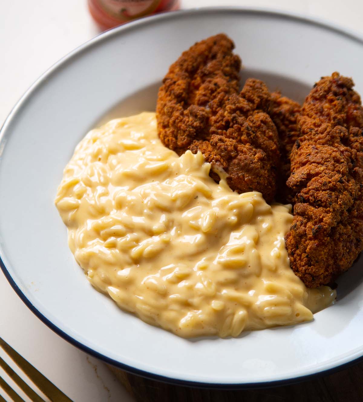 cheesy orzo served in a bowl with fried chicken tenders