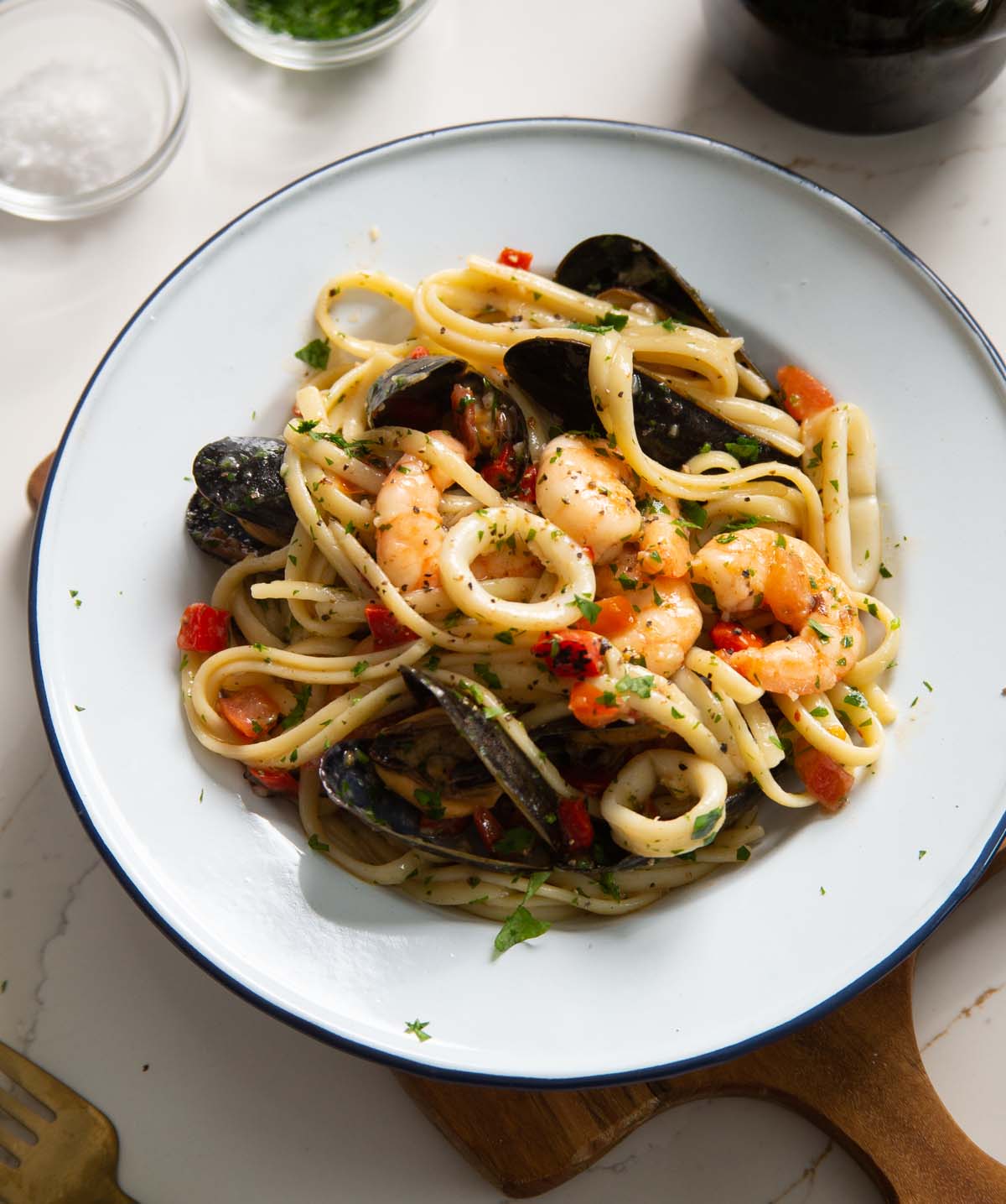 seafood pasta served in white dish on wooden chopping board