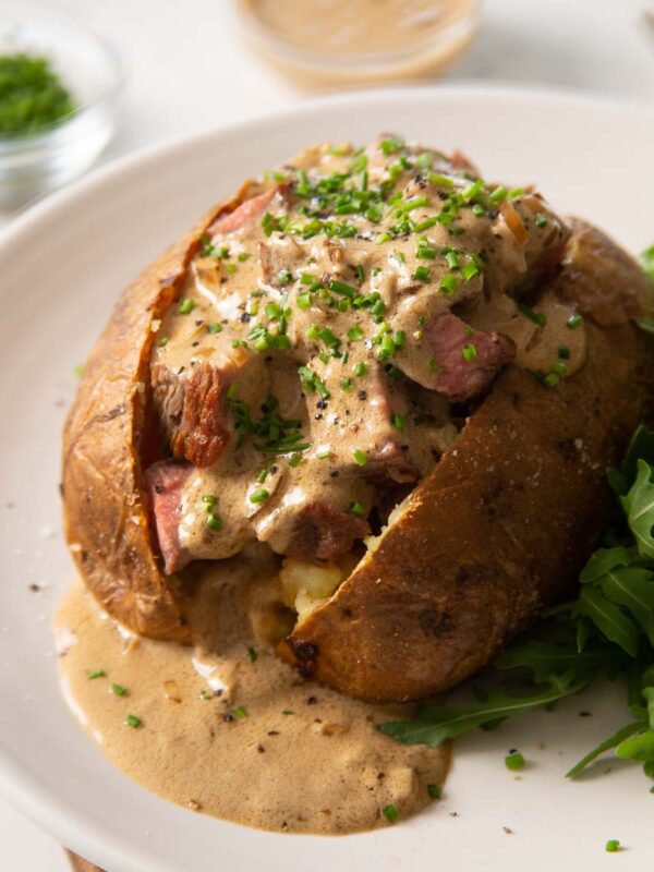 steak baked potato on small white plate with small side salad