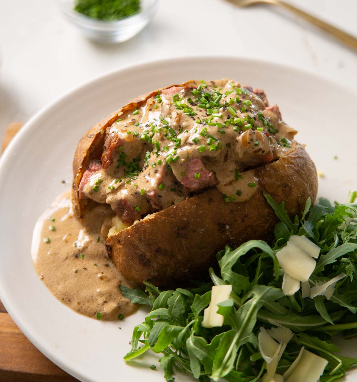 steak baked potato on small white plate with salad