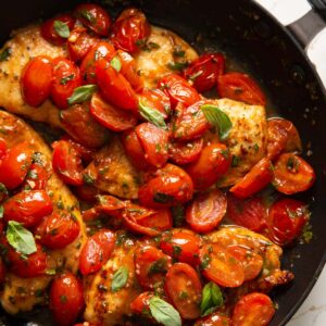 tomato basil chicken in large pan garnished with extra basil