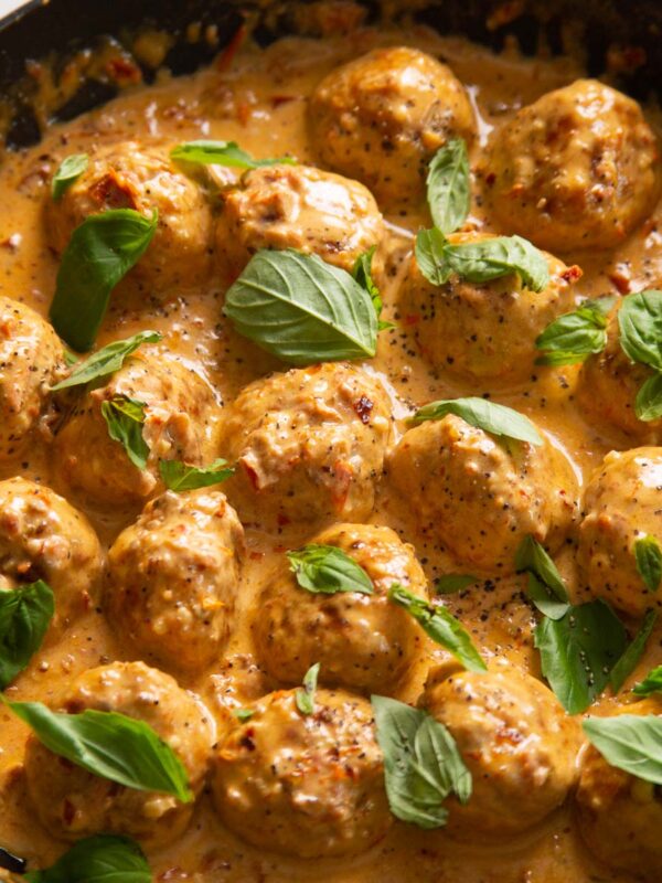 close up shot of marry me chicken meatballs in pan garnished with fresh basil