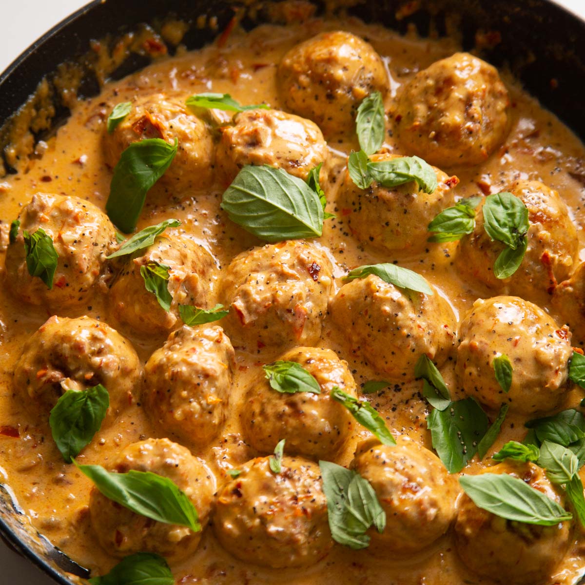 close up shot of marry me chicken meatballs in pan garnished with fresh basil