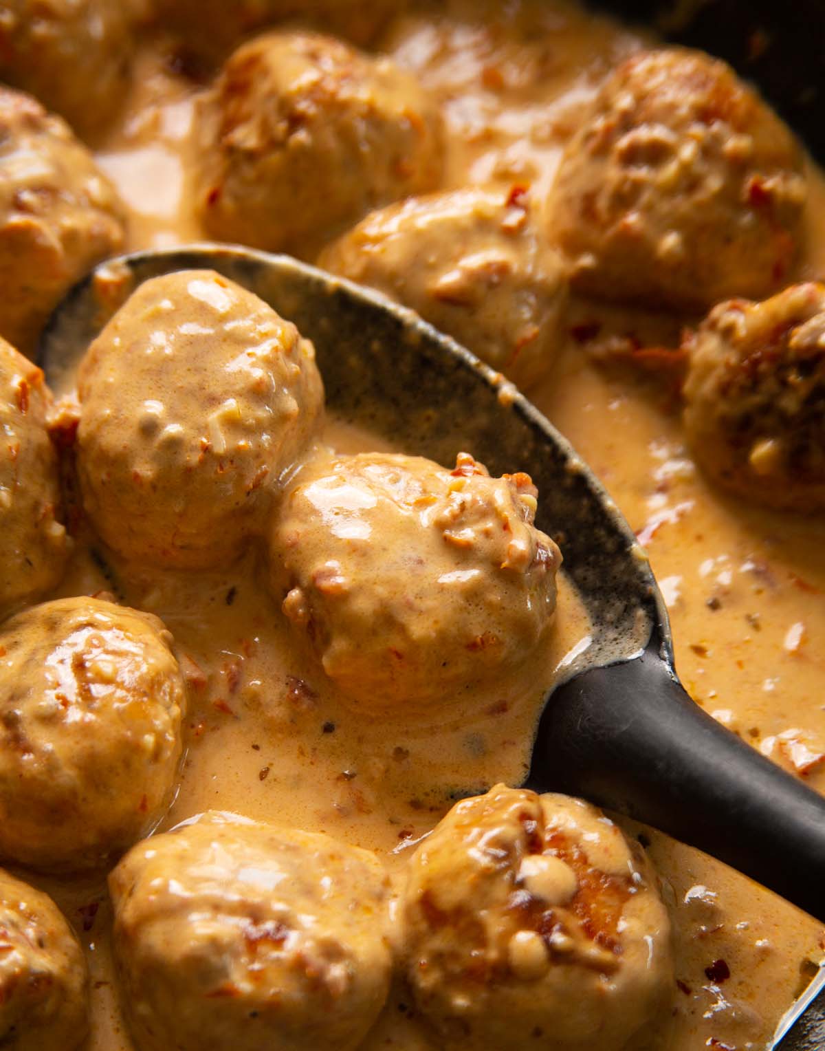 close up shot of serving spoon scooping marry me meatballs out of pan