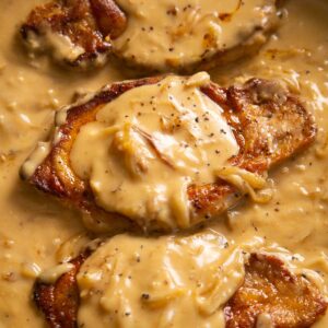 close up shot of smothered pork chops in pan