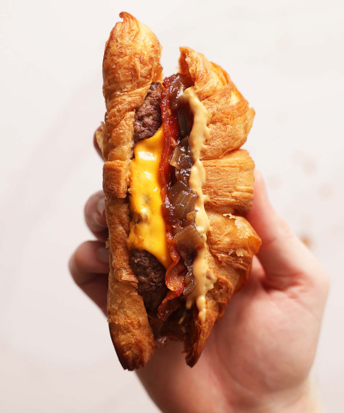 close up overhead shot of hand holding croissant burger