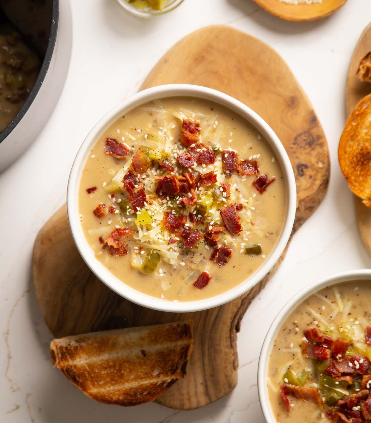 overhead shot of cheeseburger soup in small white bowl with toppings