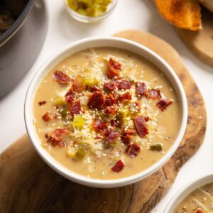close up shot of cheeseburger soup in white bowl on wooden chopping board