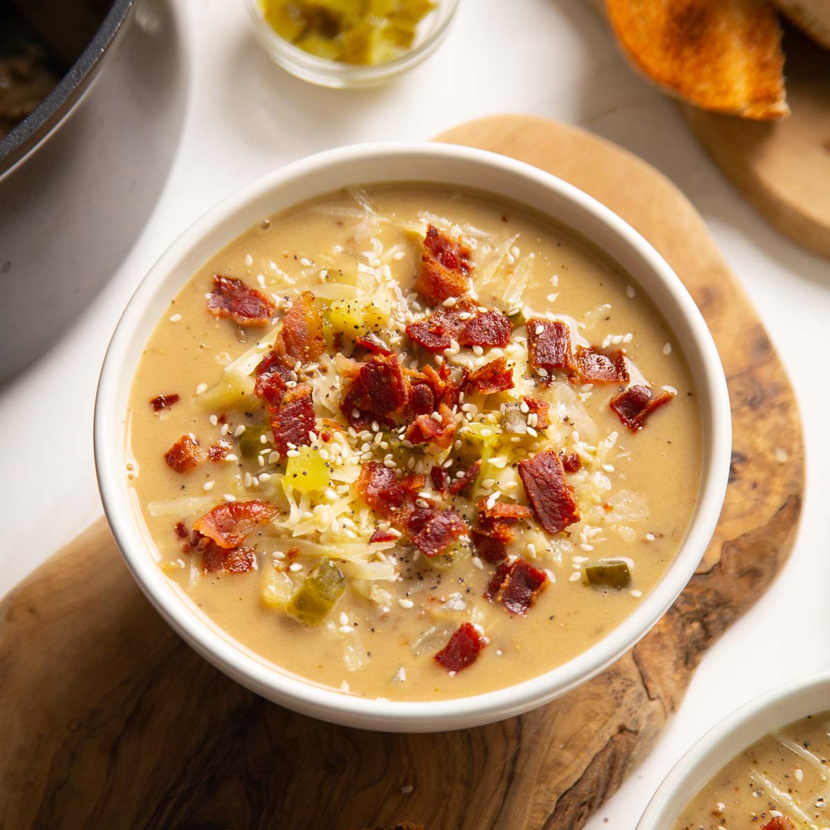 close up shot of cheeseburger soup in white bowl on wooden chopping board