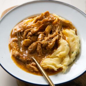 chicken and gravy served in white dish with gold fork