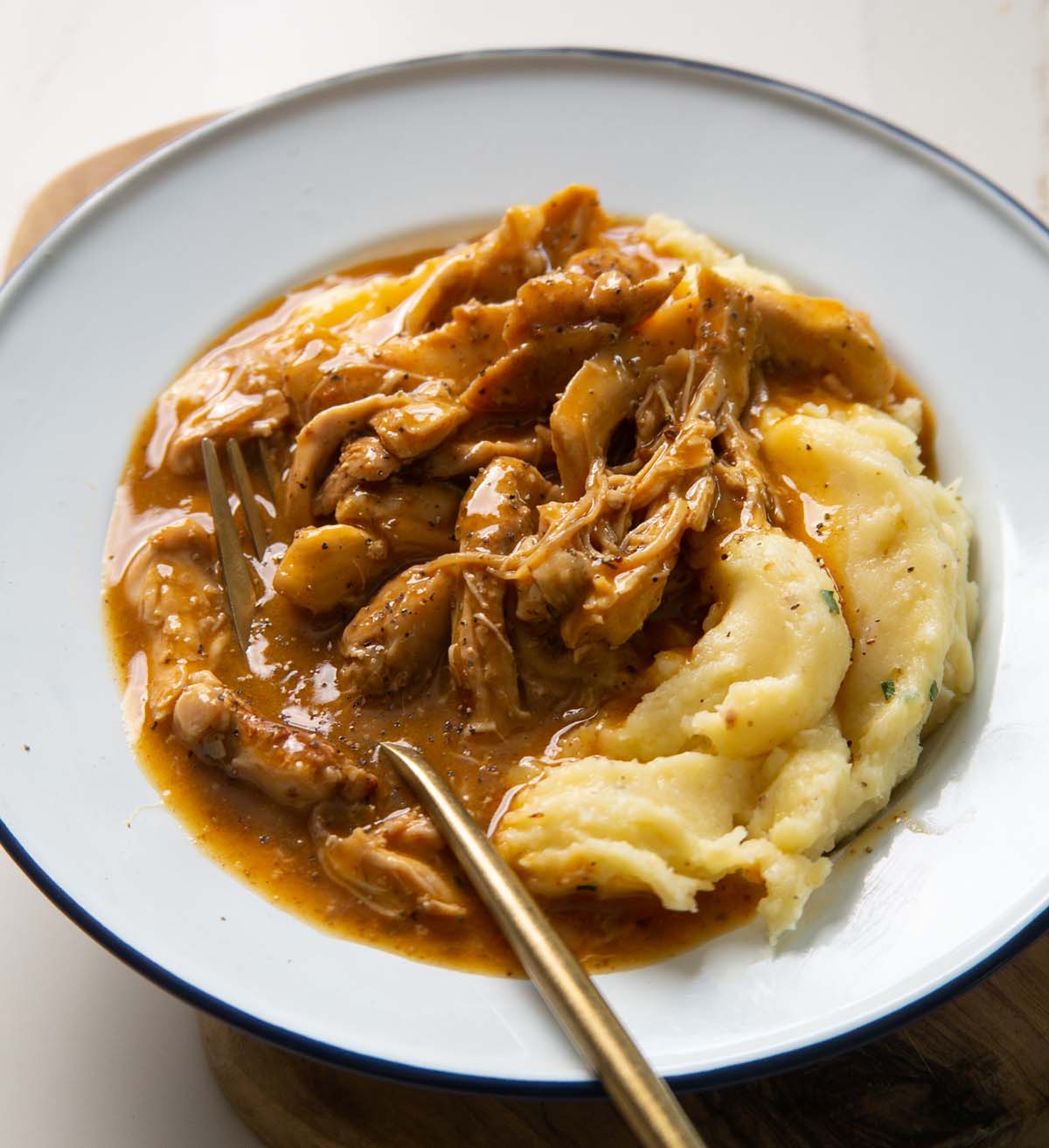 chicken and gravy served in white dish with gold fork