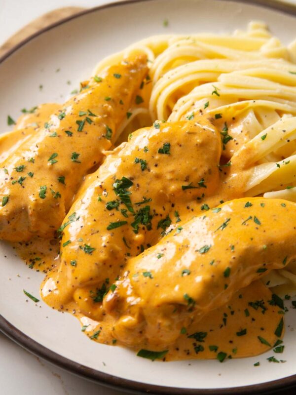 close up shot of chicken lazone with buttered noodles on small white plate