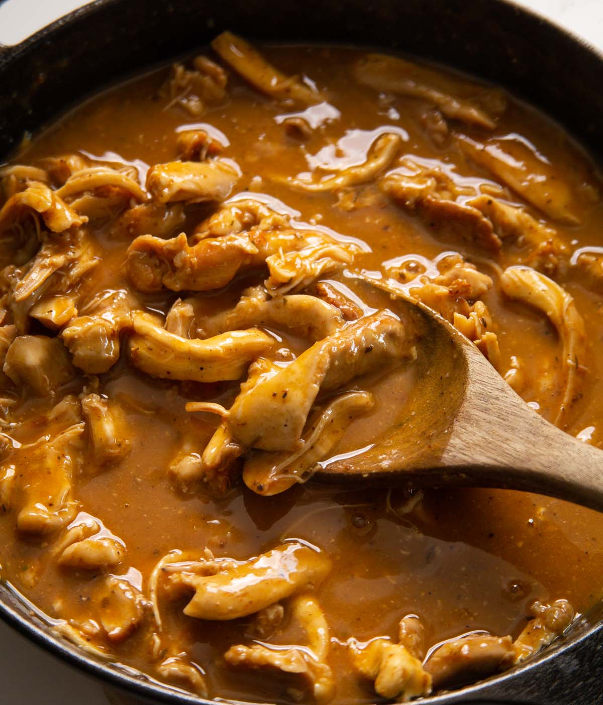 close up shot of chicken and gravy with wooden spoon digging in
