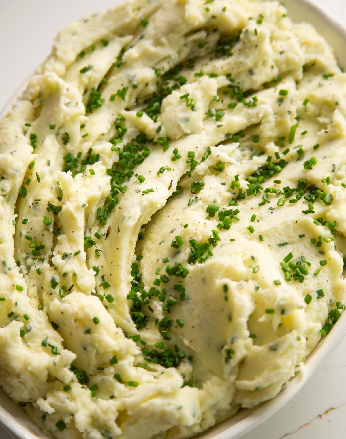 overhead shot of sour cream chive mash potatoes in large white serving dish