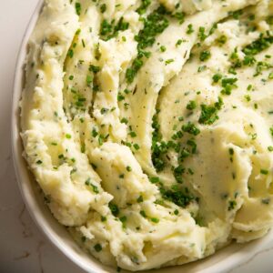 close up shot of sour cream chive mashed potatoes in large white dish
