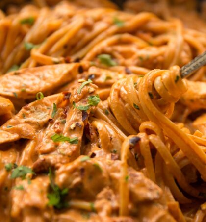 fork twizzling into chicken pasta in skillet